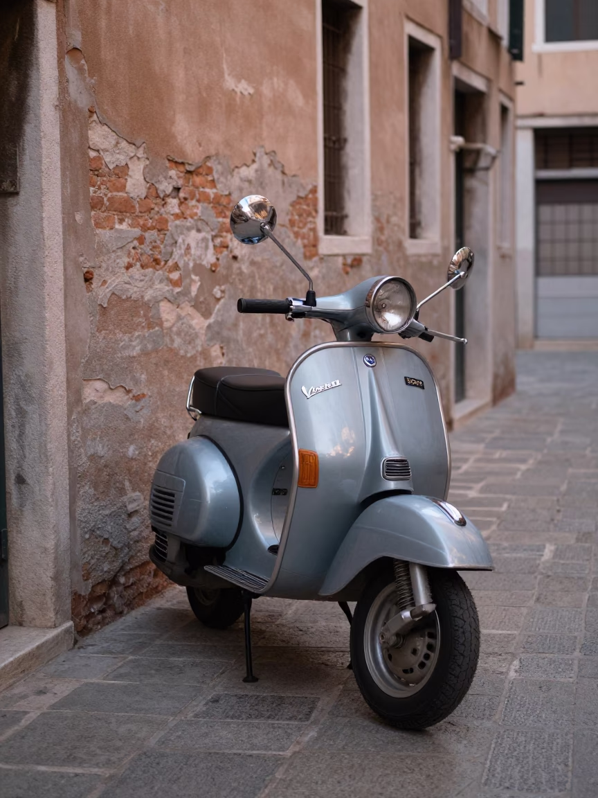 Vintage Vespa parked on narrow Venetian cobblestone lane at dawn first light in in Venice, Italy