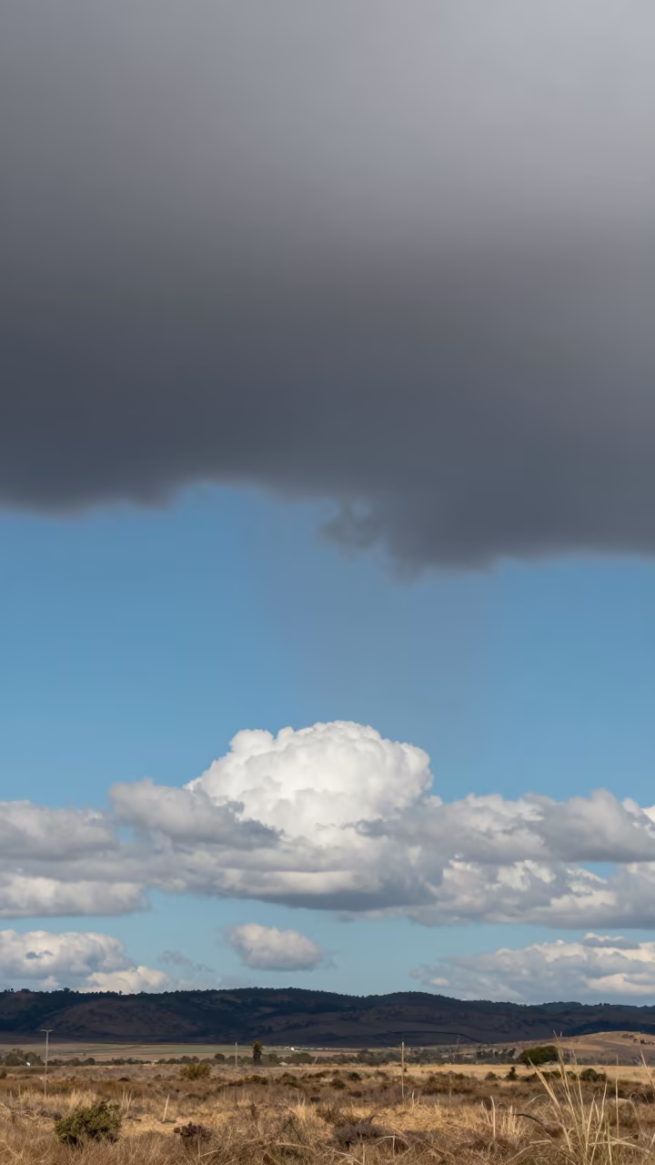 Virga Falling from Thunderheads Over Matola in over a horizon of stacked thunderheads near Matola