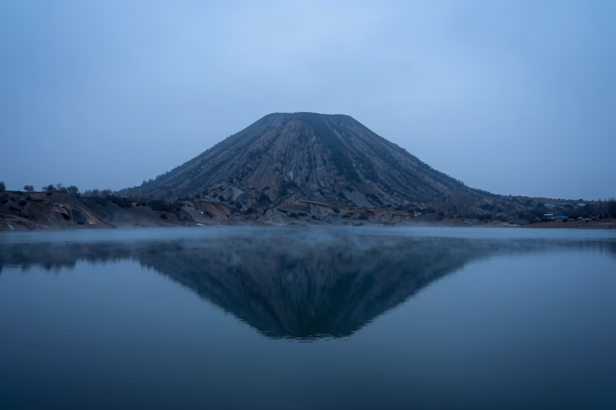 Volcanic Cone Reflected in Misty Crater Lake Himachal in across a wide valley floor in Himachal Pradesh