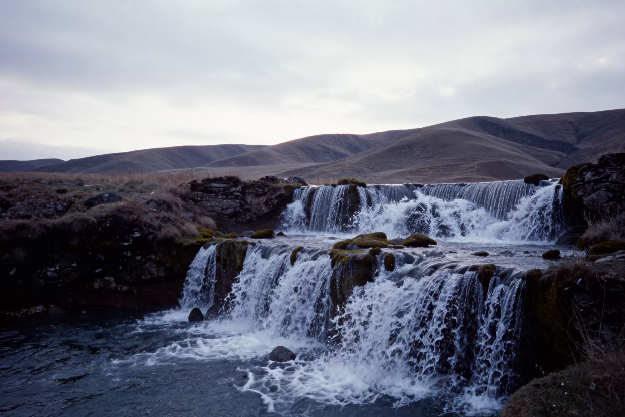 Waterfall Cascading Over Mossy Terraces Near Almaty in from a ridge above layered foothills near Almaty
