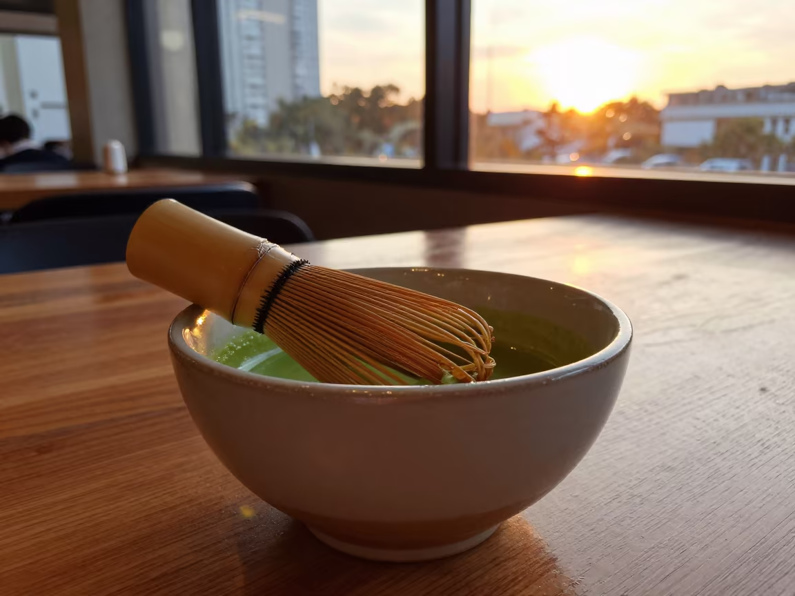 Whisked Matcha Bowl in São Paulo Sunset in on a small cafe table by a window in São Paulo