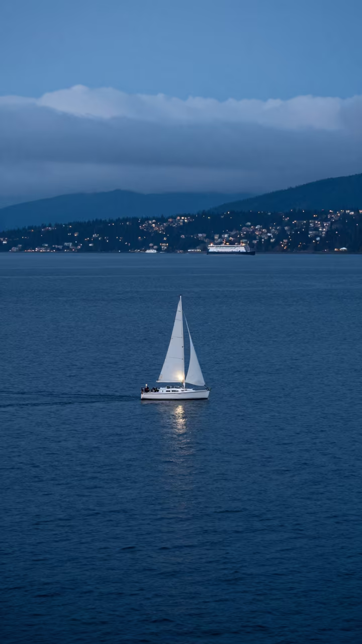 White Sailboat on Deep Blue Sea at Twilight in across a remote ferry crossing in British Columbia