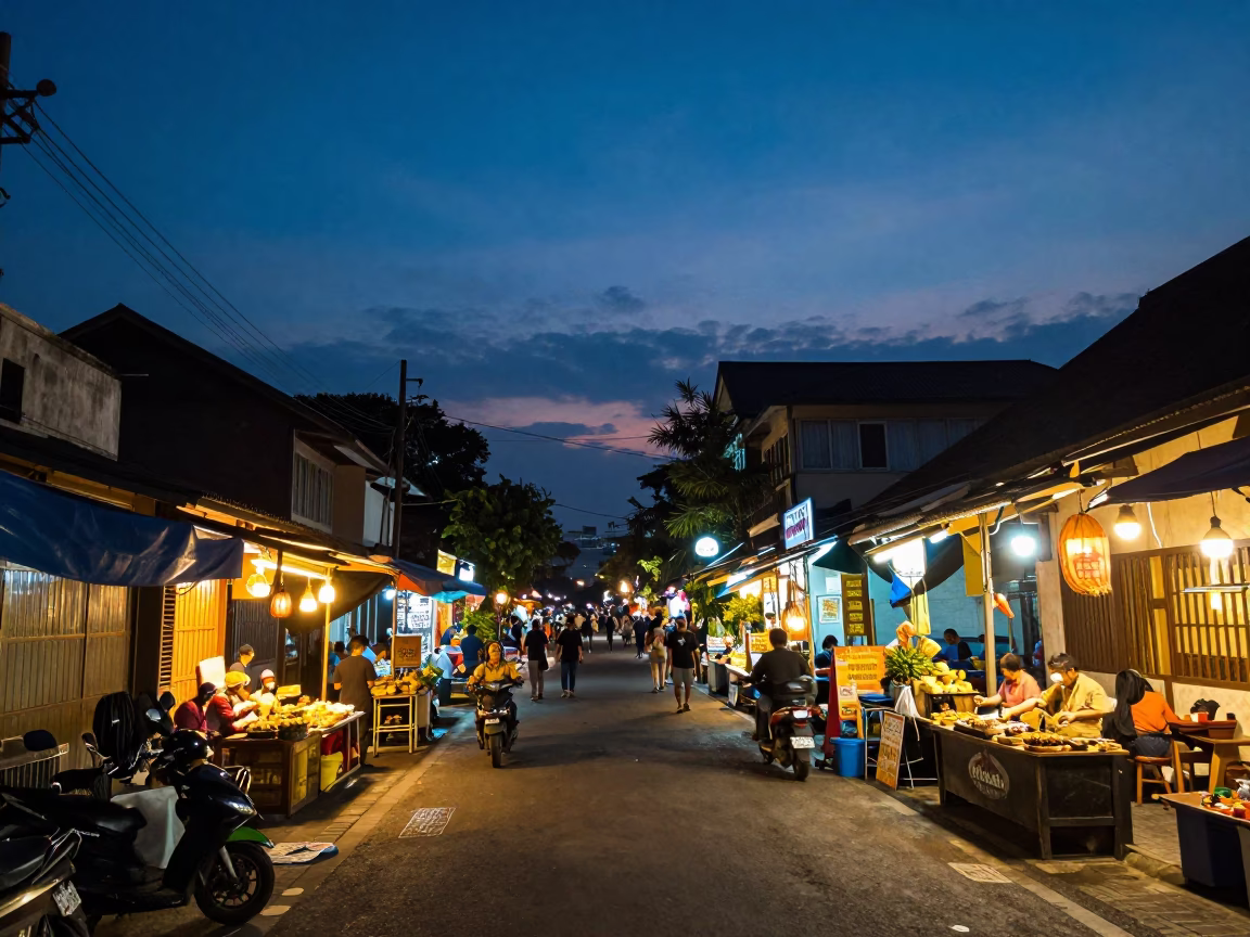 Yogyakarta Indonesia street scene at dusk with glowing shop lights and passing motorcycle traffic in in Yogyakarta, Indonesia
